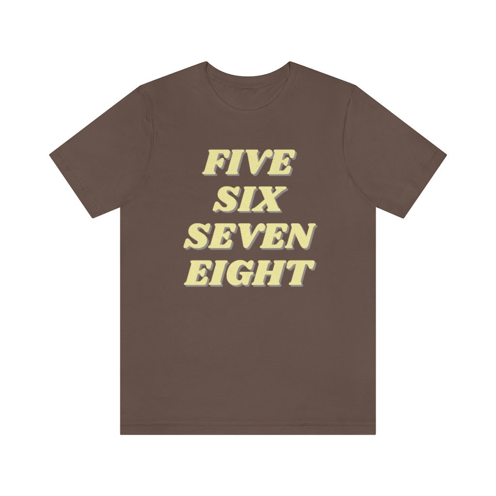A brown T-shirt with the text "five sixe seven eight" in yellow text. It refers to the counting in of either music or dance.