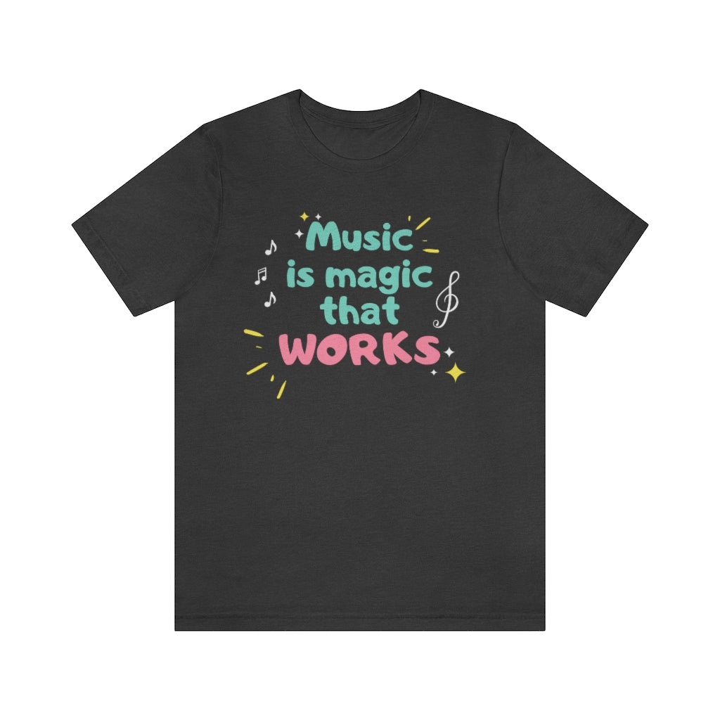 A dark grey T-shirt with the text "music is magic that works!". It has a childish and playful design with music notes and treble clefs surrounding it.