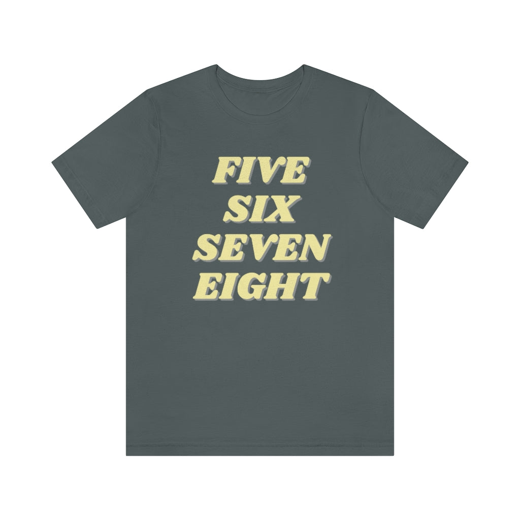 A light grey T-shirt with the text "five sixe seven eight" in yellow text. It refers to the counting in of either music or dance.