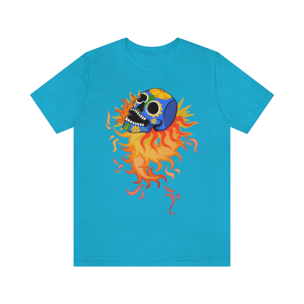 A light blue T-shirt with a mexican alibrije style dia del muerte skull. It is traveling and leaves behind a spiral of fire.